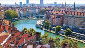 A river flowing through a city with historic buildings and a modern skyscraper in the background. - Room in a Stunning Apartment in the City and the Countryside (Oullins-Pierre-Bénite)