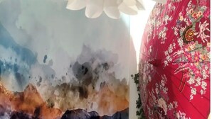 A room with a large abstract painting, a floral umbrella, and a wooden table with a plant and a photo frame. - Room in a Stunning Apartment in the City and the Countryside (Oullins-Pierre-Bénite)