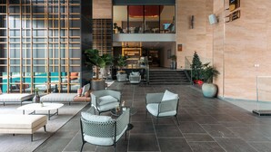 Una hall moderna con area salotto, scrivania della reception e una scala che conduce a un piano superiore.