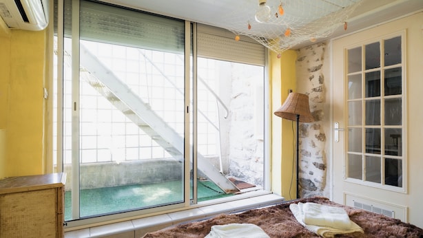 Ein Zimmer mit großem Fenster, einer äußeren Treppe, einer Lampe und einem Bett mit Decke.