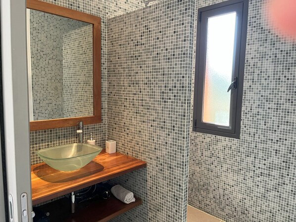 A bathroom with a glass bowl sink, wooden vanity, and a mirror with a wooden frame. - Les Hauts de la Testa (Sainte-Lucie de Porto-Vecchio)