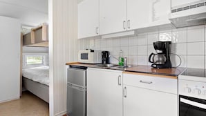 Une petite cuisine équipée avec des meubles blancs, un four à micro-ondes, une machine à café et un petit four.
