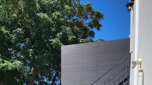 A concrete staircase leading to a building with a corrugated metal exterior and a metal railing.