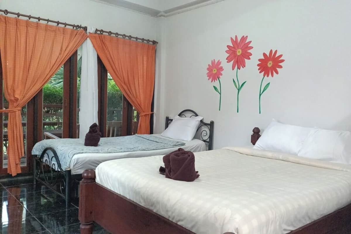 Une chambre avec deux lits, des rideaux orange et un mur décoré de motifs floraux.