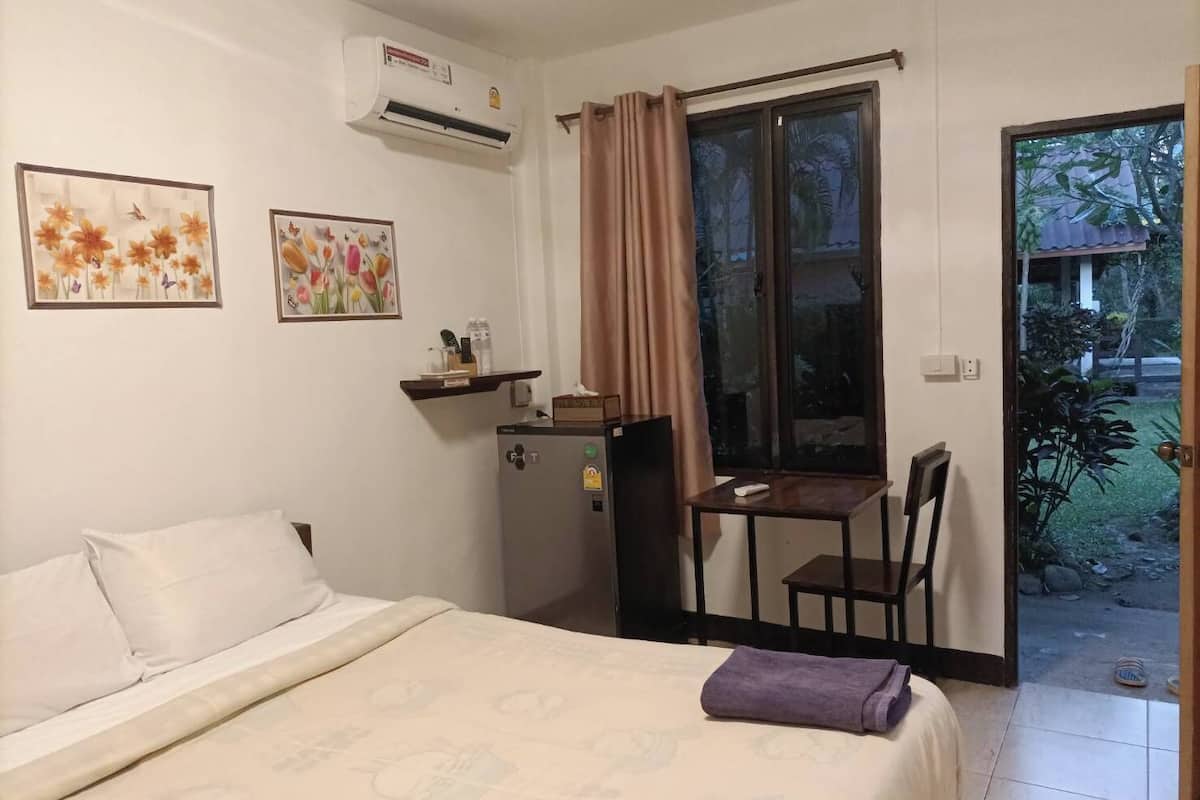 Une chambre à coucher comprenant un lit, un bureau, une chaise, une fenêtre avec des rideaux et un appareil de climatisation.
