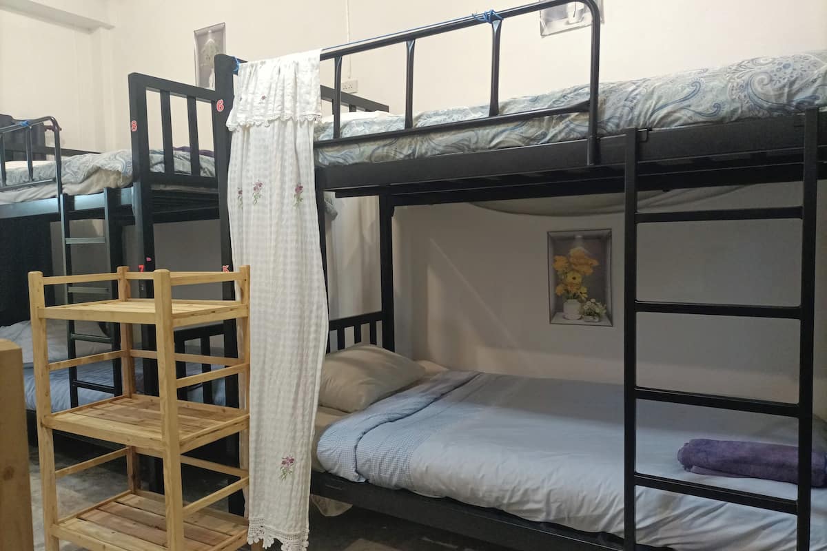 Une chambre avec un lit superposé, une chaise en bois et une petite étagère.