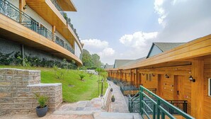 A hotel with wooden exterior walls, balconies with wrought iron railings, and a stone pathway leading to the entrance.