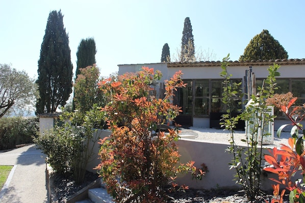 A modern building with a white facade, large windows, and a garden with various plants and trees. - Villa 45 (La Colle-sur-Loup)