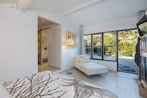 Un dormitorio moderno con un ventanal grande, un sofá blanco y vistas al exterior.