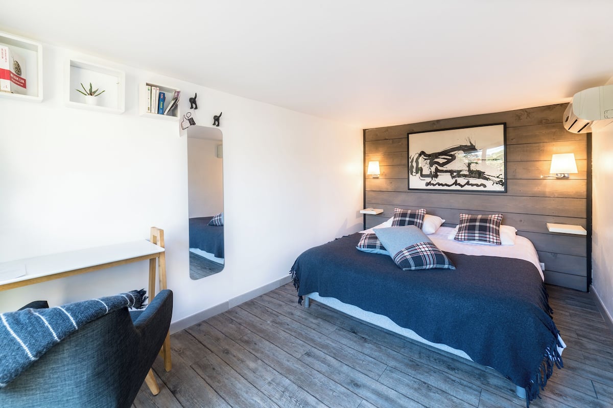 A bedroom with a bed, bedside tables, a desk, and a chair.