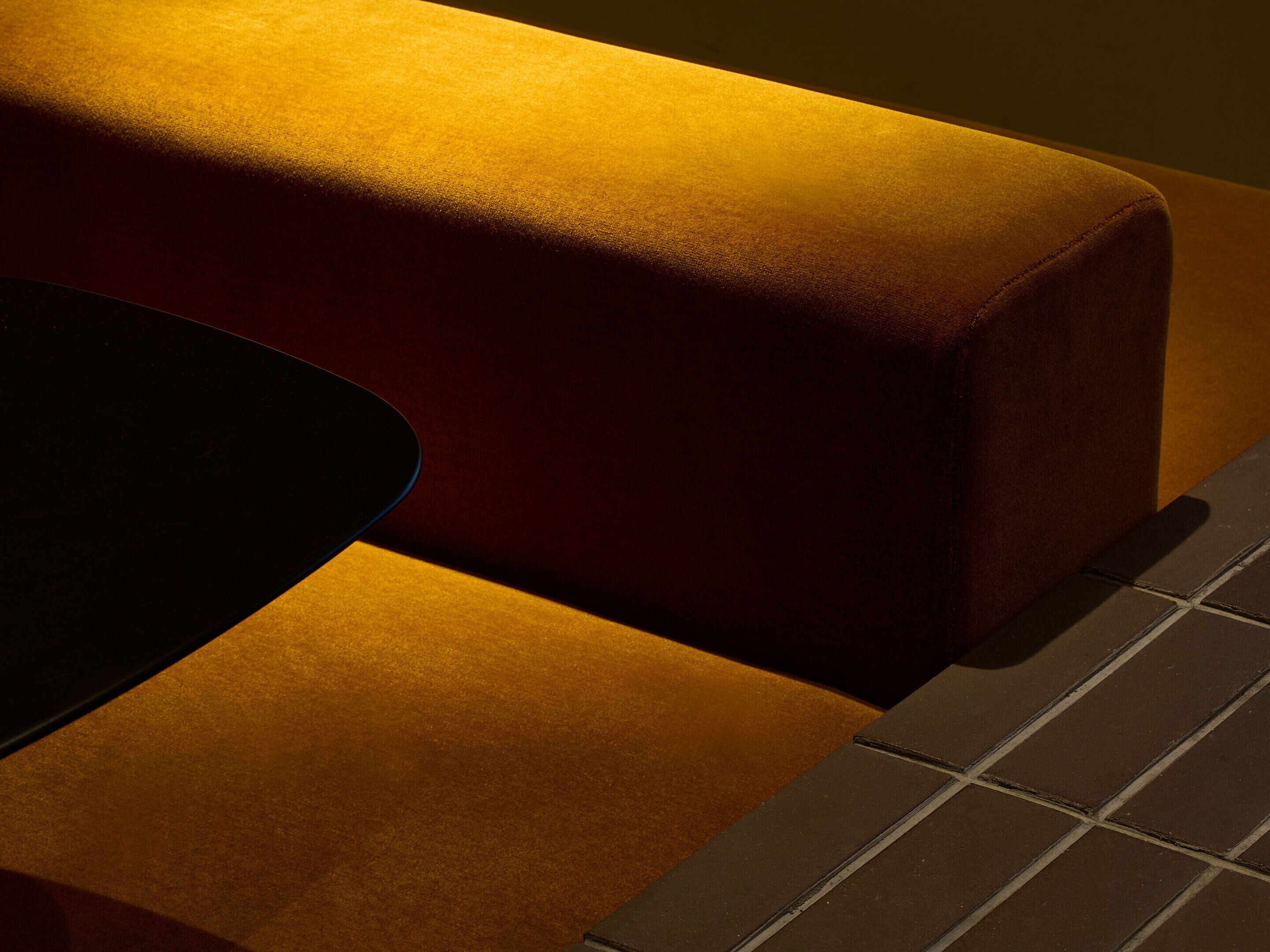 Eine Nahaufnahme eines Sofas mit dunklem Kissen und Fliesenboden.