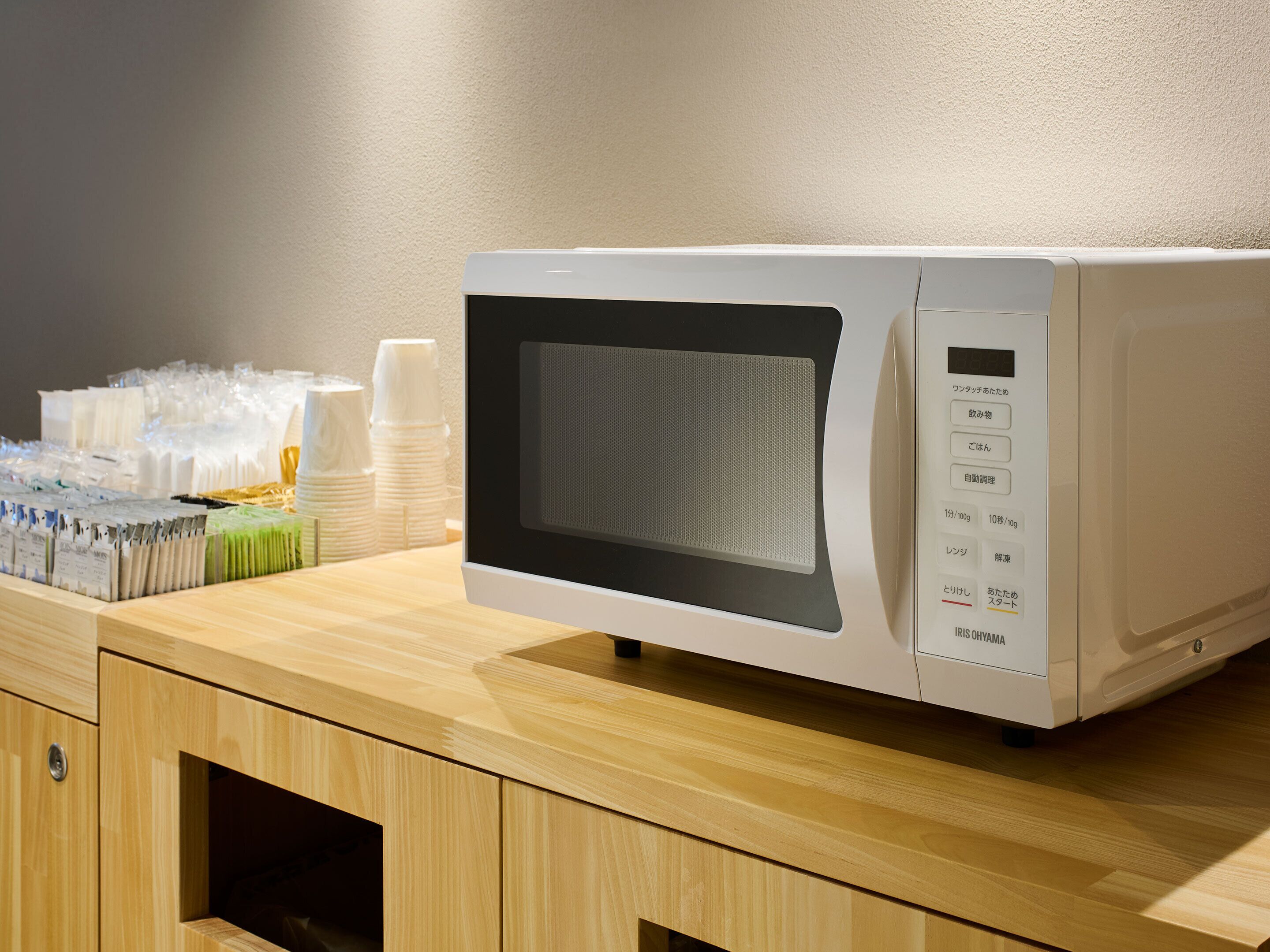 A microwave on a wooden counter with a wall in the background.
