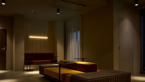 Habitación de hotel con cama, una mesita, un sofá, una lámpara de pie y una puerta.
