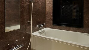 Un baño moderno con una bañera grande, un espejo montado en la pared y un cabezal de ducha.