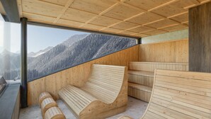 Un sauna avec des bancs en bois et une grande fenêtre donnant sur les montagnes.
