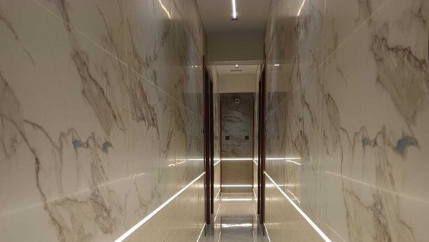 A corridor with marble walls and a polished floor, leading to an elevator. - Hotel Grand Palace Inn (Mumbai)