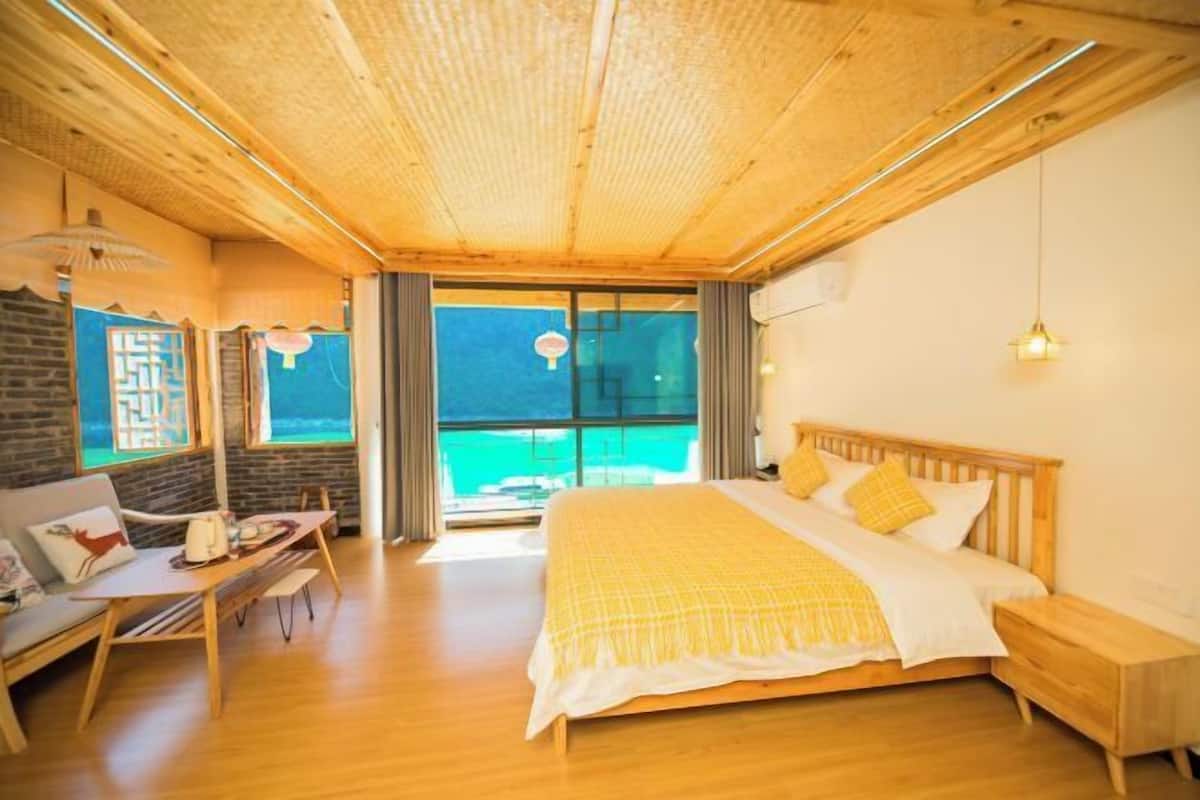 A room with a bed, a desk, a chair, and a view of the sea.