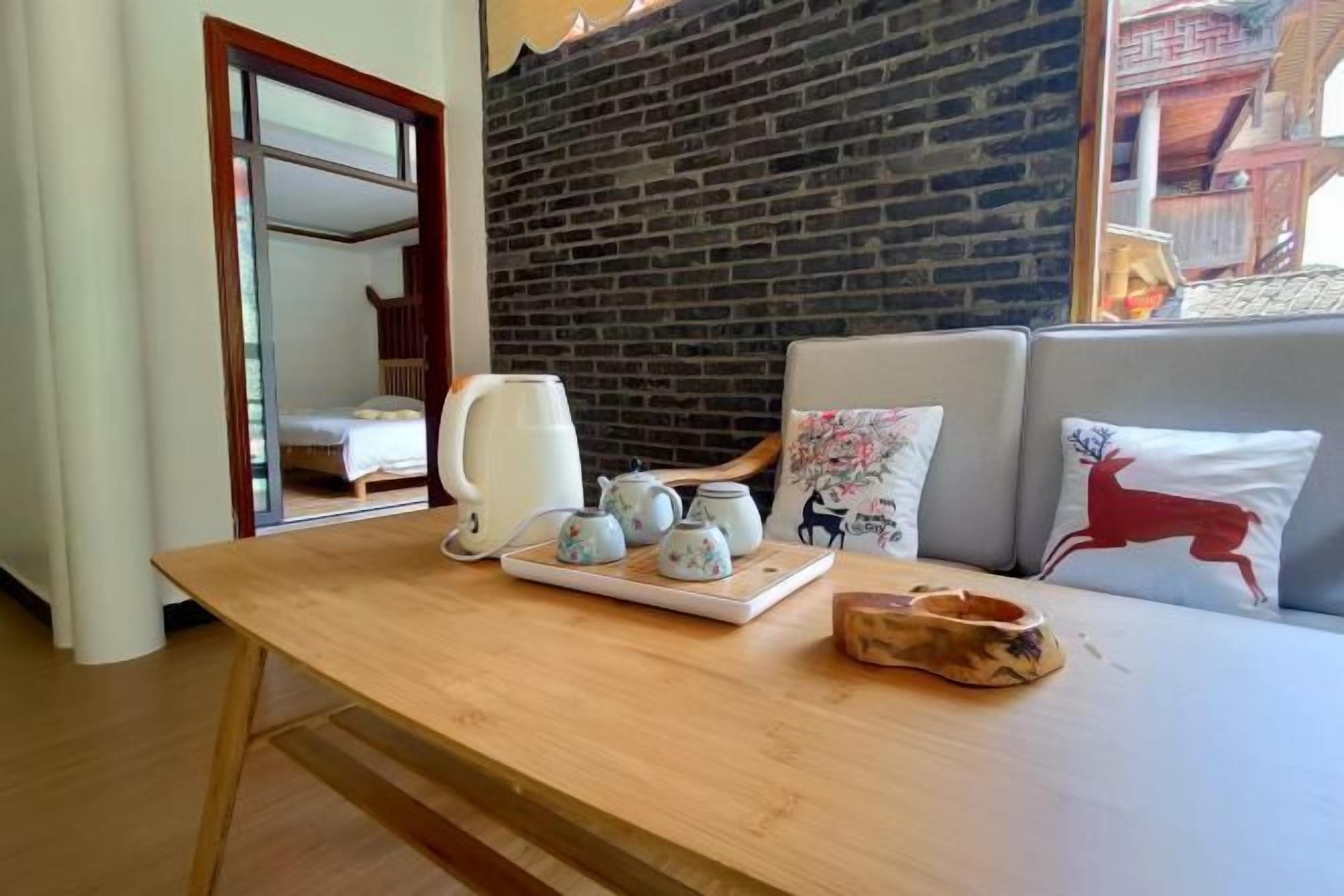 Une table en bois sur laquelle se trouve un plateau avec des théières, une bouilloire blanche et un bol en bois.