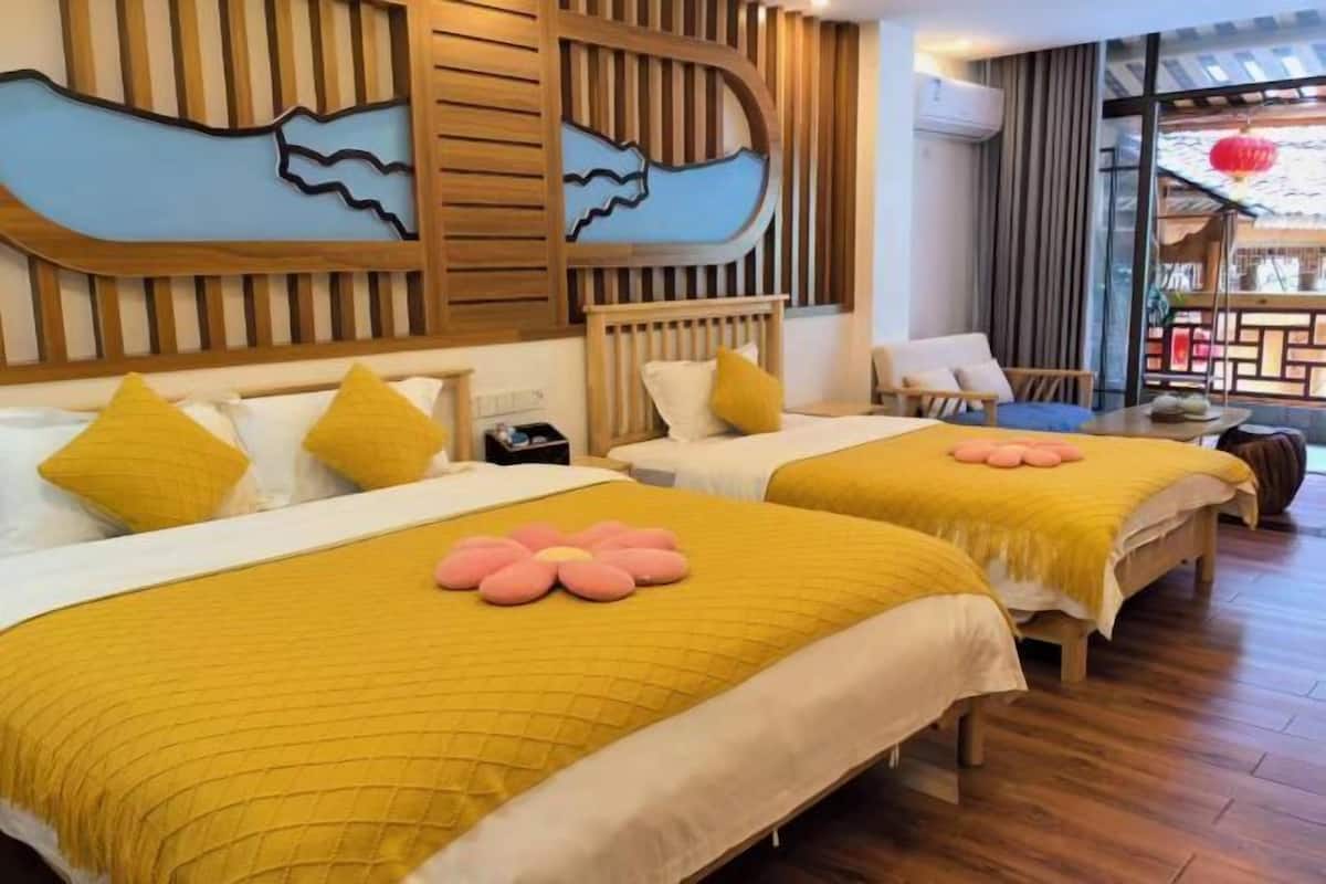 A hotel room with two beds, wooden headboards, and a view of the outside.