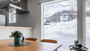 A modern kitchen with a large window overlooking a snowy landscape.