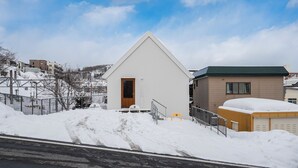 A modern building with a triangular roof, a wooden door, and a small porch.