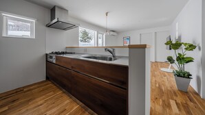 A modern kitchen with wooden cabinets, a stainless steel sink, and a window overlooking a snowy landscape.
