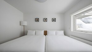 A double bed with white bedding, a bedside lamp, and three framed pictures on the wall.