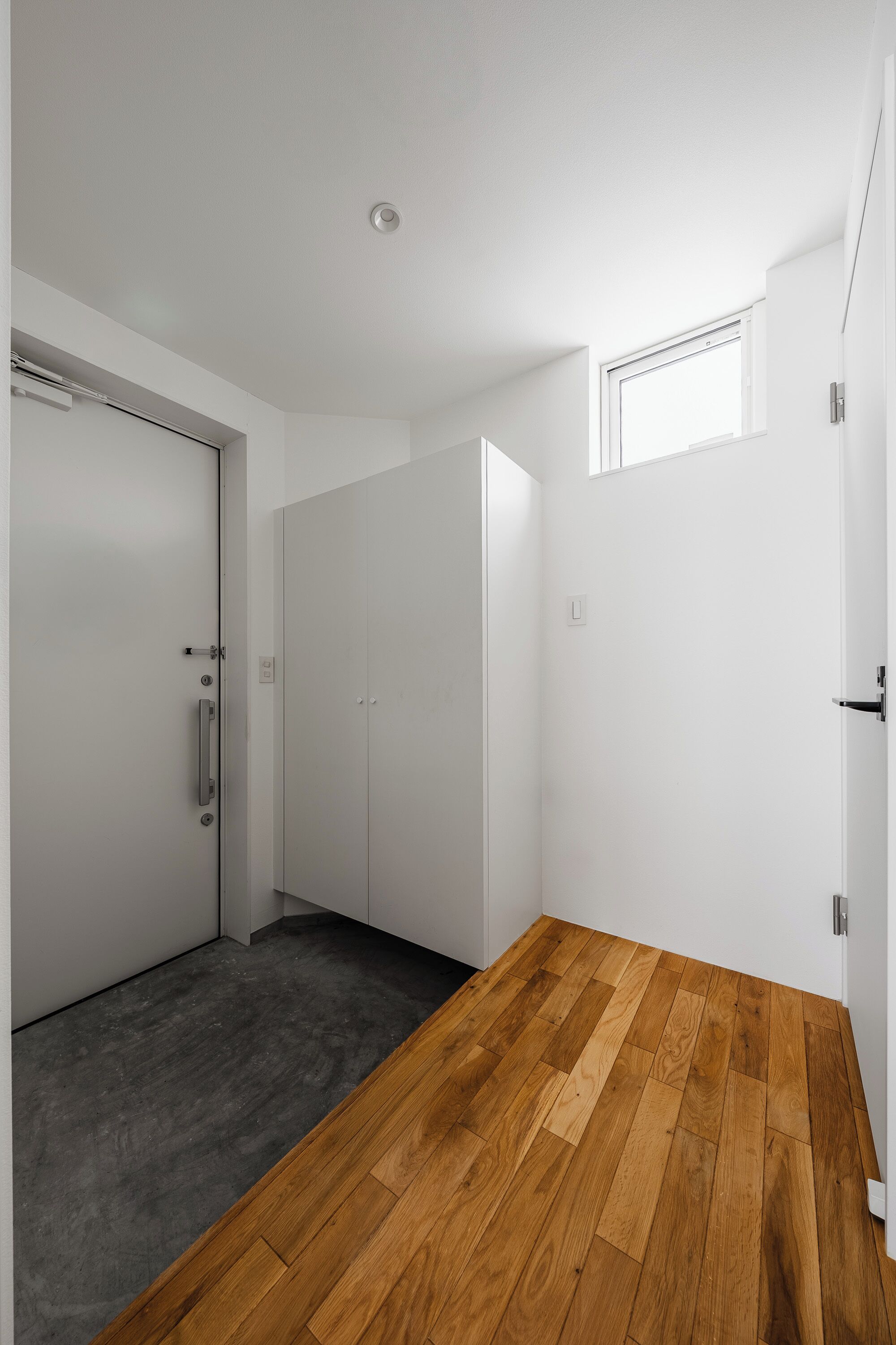A room with a wooden floor, white walls, and a door with a handle.