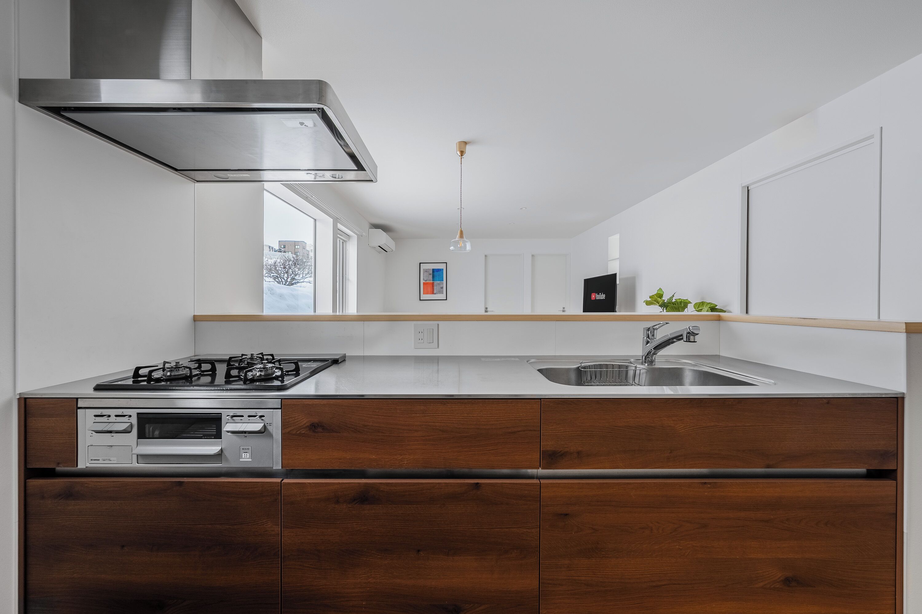 A modern kitchen with a stainless steel range hood, a built-in oven, and a double sink.