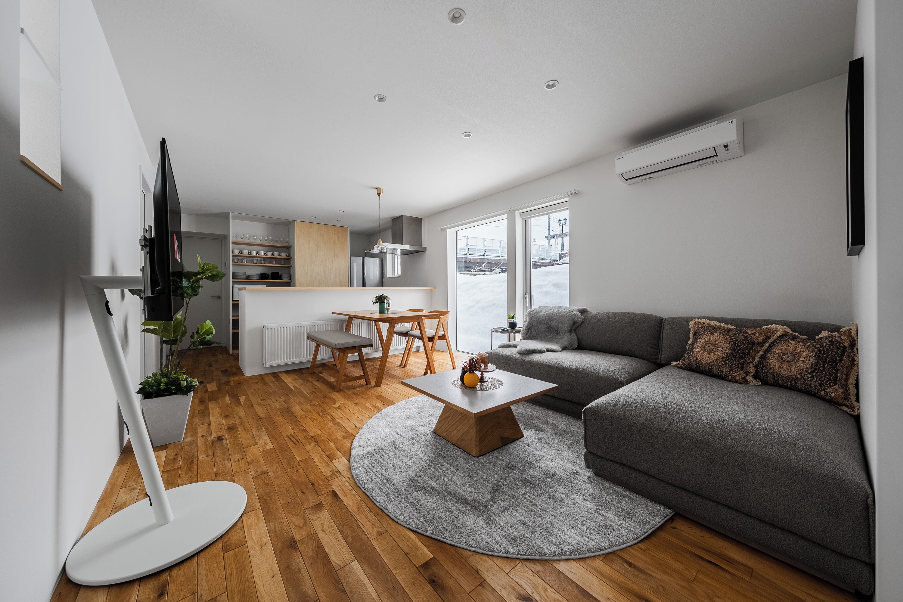 A modern living room with a gray sofa, a round coffee table, and a wooden floor.