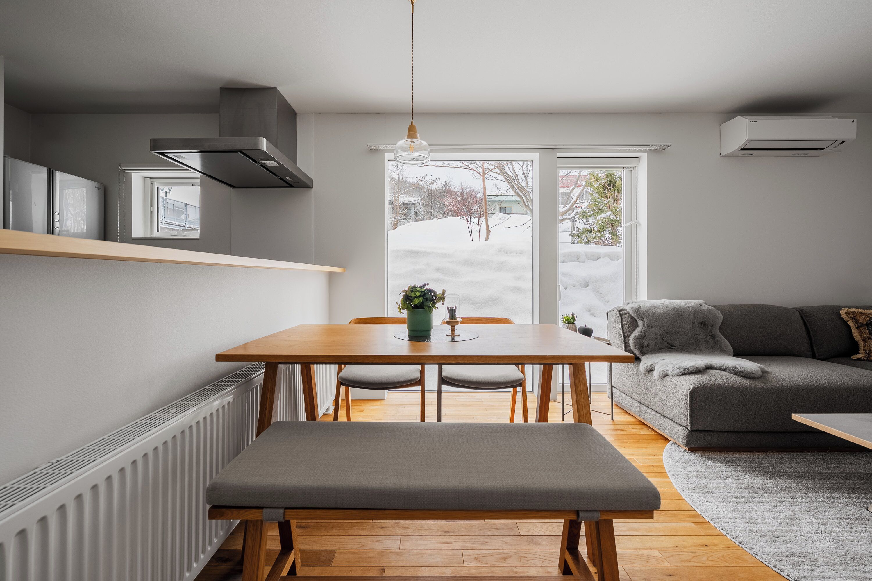 A modern kitchen with a dining table, bench, and built-in appliances.