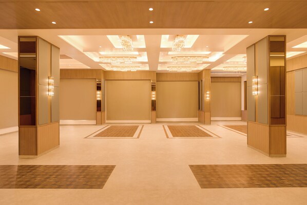 A spacious hotel lobby with a modern design, featuring a central open area, wooden paneling, and decorative lighting fixtures. -  Keys Select by Lemon Tree Hotels Vadodara (Vadodara)
