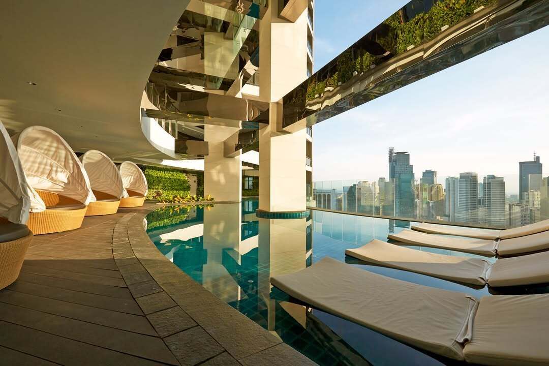 A modern rooftop pool area with lounge chairs and a city view.