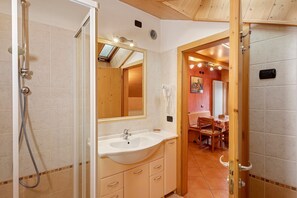 Une salle de bain avec une douche, un lavabo et une porte en bois.