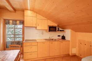 A kitchen with wooden cabinets, a microwave, and a sink. - Chalet 'Romeo' with Mountain View and Wi-Fi (Livigno)