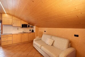 Een keuken met houten kasten, een magnetron en een bank in een knusse kamer.