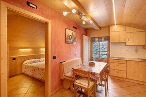 A cozy room with a bed, a bench, a dining table, and wooden cabinets. - Chalet 'Romeo' with Mountain View and Wi-Fi (Livigno)