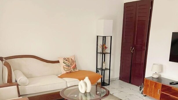 A living room with a sofa, a round coffee table, two ottomans, a cabinet, and a wardrobe.
