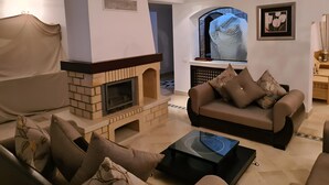 A living room with a fireplace, a sofa, and a coffee table. - VILLA L'OLIVIER (Kelibia)