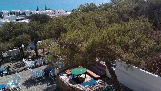 A terrace with outdoor seating, a view of the sea, and white buildings in the background. - VILLA L'OLIVIER (Kelibia)