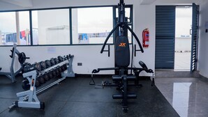 A gym with weightlifting equipment, a fire extinguisher, and a view of the outside. - Serene Executive 1BR in Upscale Kileleshwa (PQ9M+R3 Nairobi)