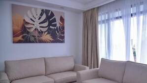 A living room with two sofas, a coffee table, and a large abstract painting on the wall. - Serene Executive 1BR in Upscale Kileleshwa (PQ9M+R3 Nairobi)