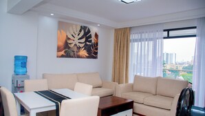 A modern living room with a sofa, a coffee table, a water dispenser, and a large window with a view. - Serene Executive 1BR in Upscale Kileleshwa (PQ9M+R3 Nairobi)