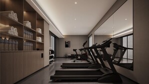 A modern gym with treadmills, a wall-mounted exercise bike, and shelves with water bottles. - Dream Palace Ben Thanh Grand Hotel (Ho Chi Minh City)