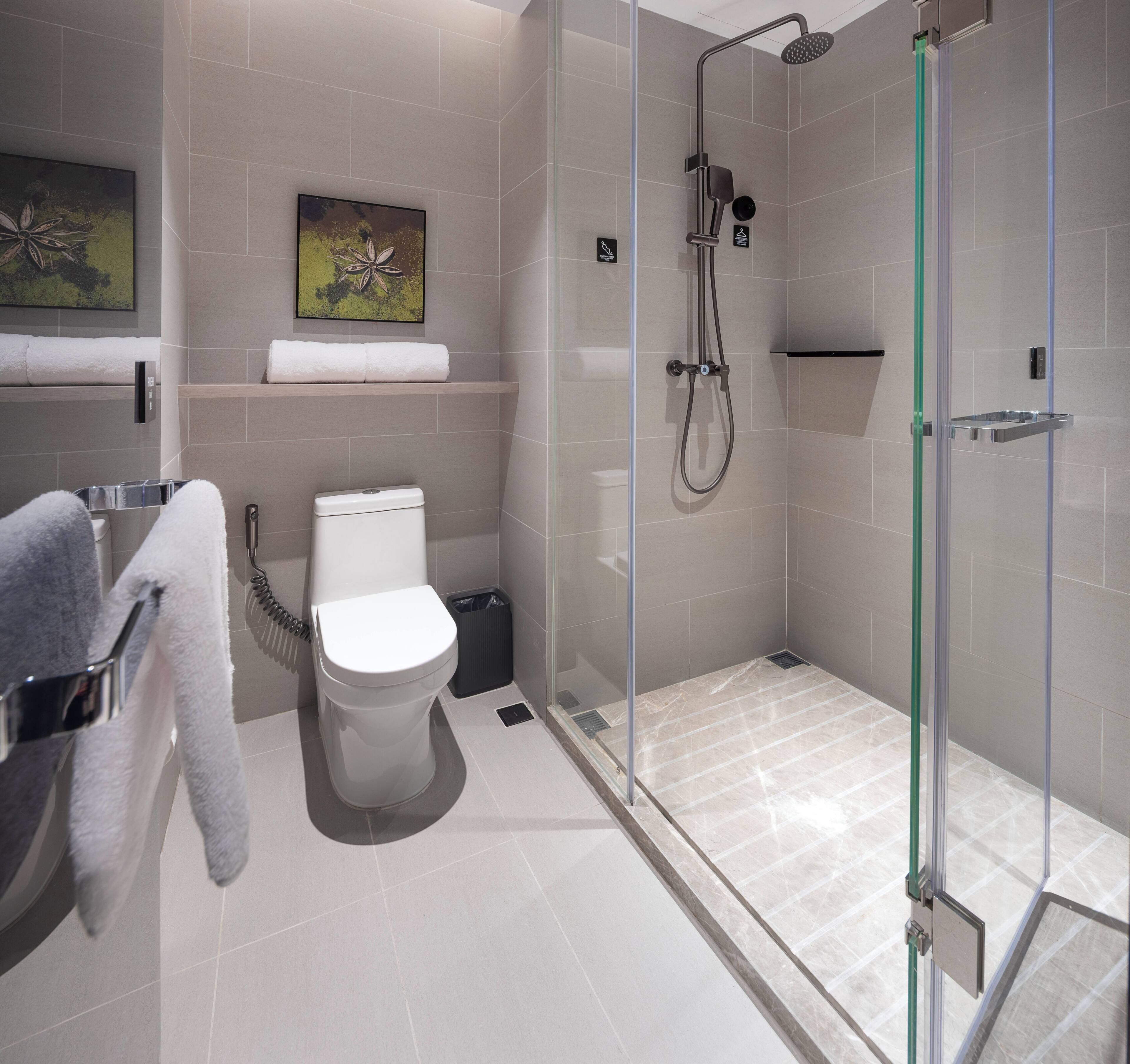 Un baño moderno con inodoro, ducha con cerramiento de vidrio y un perchero para toallas.