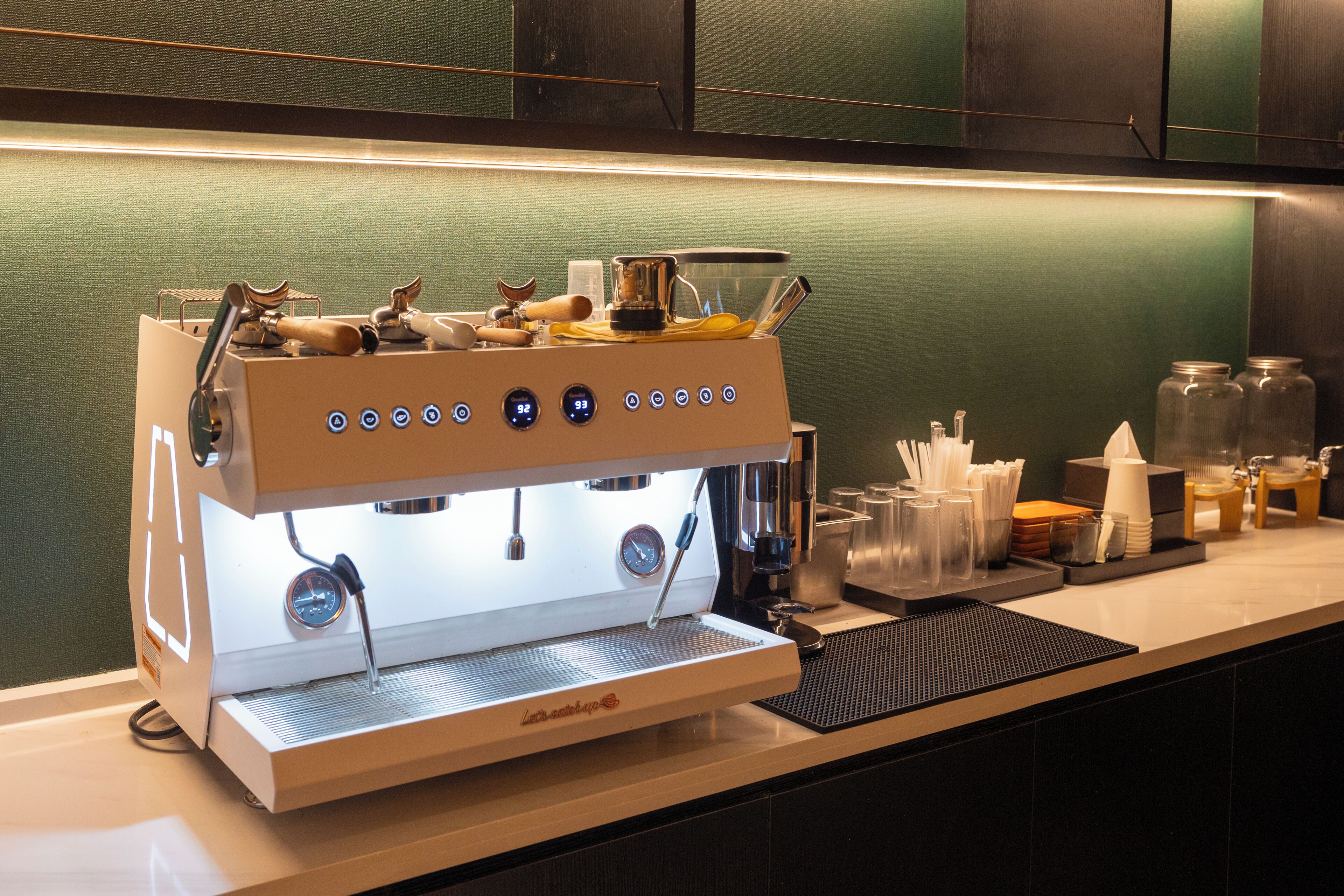 Een koffiemachine met digitale bediening, een melkopschuimer en een stoompijp op een aanrecht.