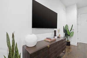Ein modernes Wohnzimmer mit einem dunklen Holzschrank, einer großen weißen Vase und einem flachbildfernseher an der Wand.