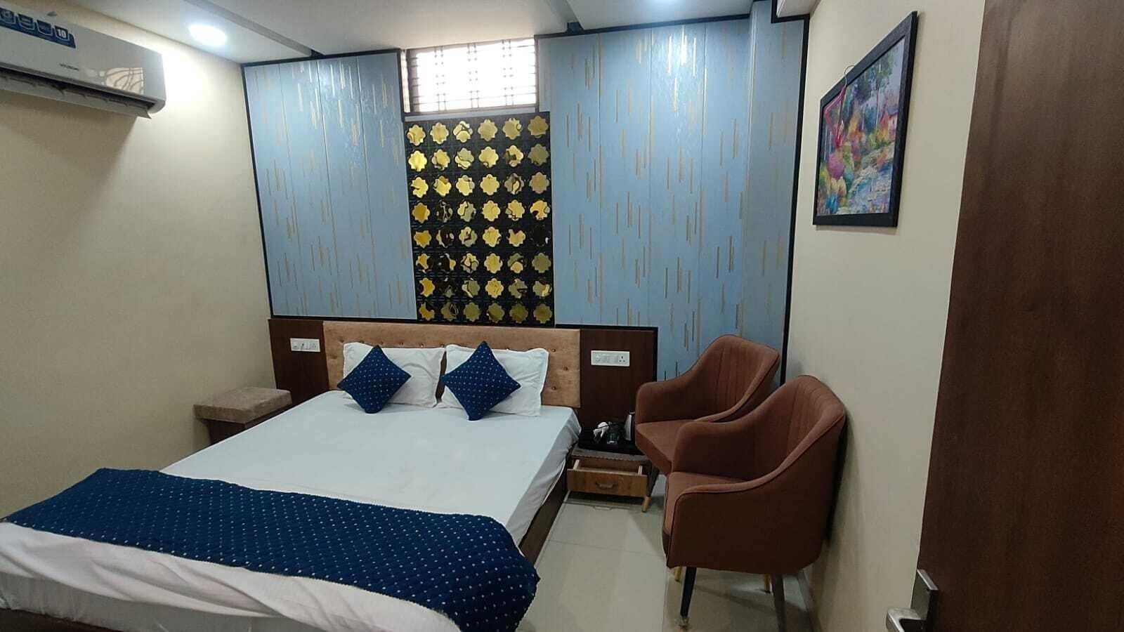 Ein Schlafzimmer mit einem Bett, zwei Kissen, einem Sessel, einem Nachttisch und einer Wand-Klimaanlage.