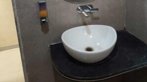 Un baño con un espejo redondo, un lavamanos y un dispensador de toallas.