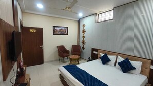 Una habitación de hotel con una cama, dos sillas, una mesita, un televisor y una puerta con el número 101.